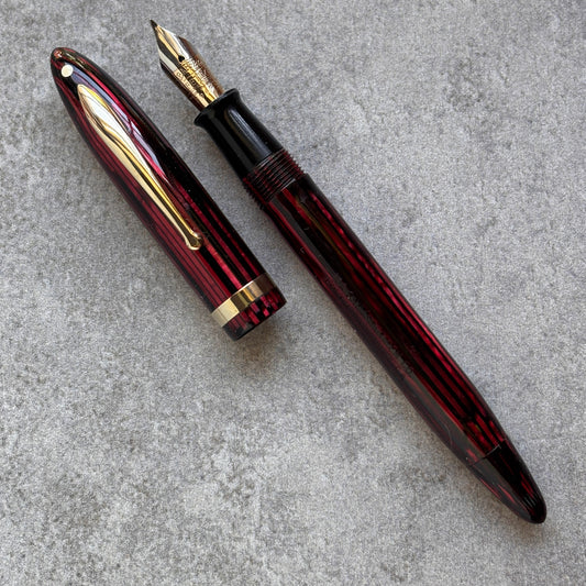 Red and gold fountain pen on a gray surface