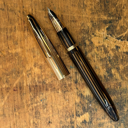Sheaffer Crest, Golden BrownName/Type: Sheaffer Crest Manufacture Year: 1940s Length: 4 7/8 Filling System: Vac-fil, restored. Color/Pattern: Golden Brown Striated with gold-filled cap Nib Type/Condition and Remarks: Two-tone fine Triumph 14K nib, writes