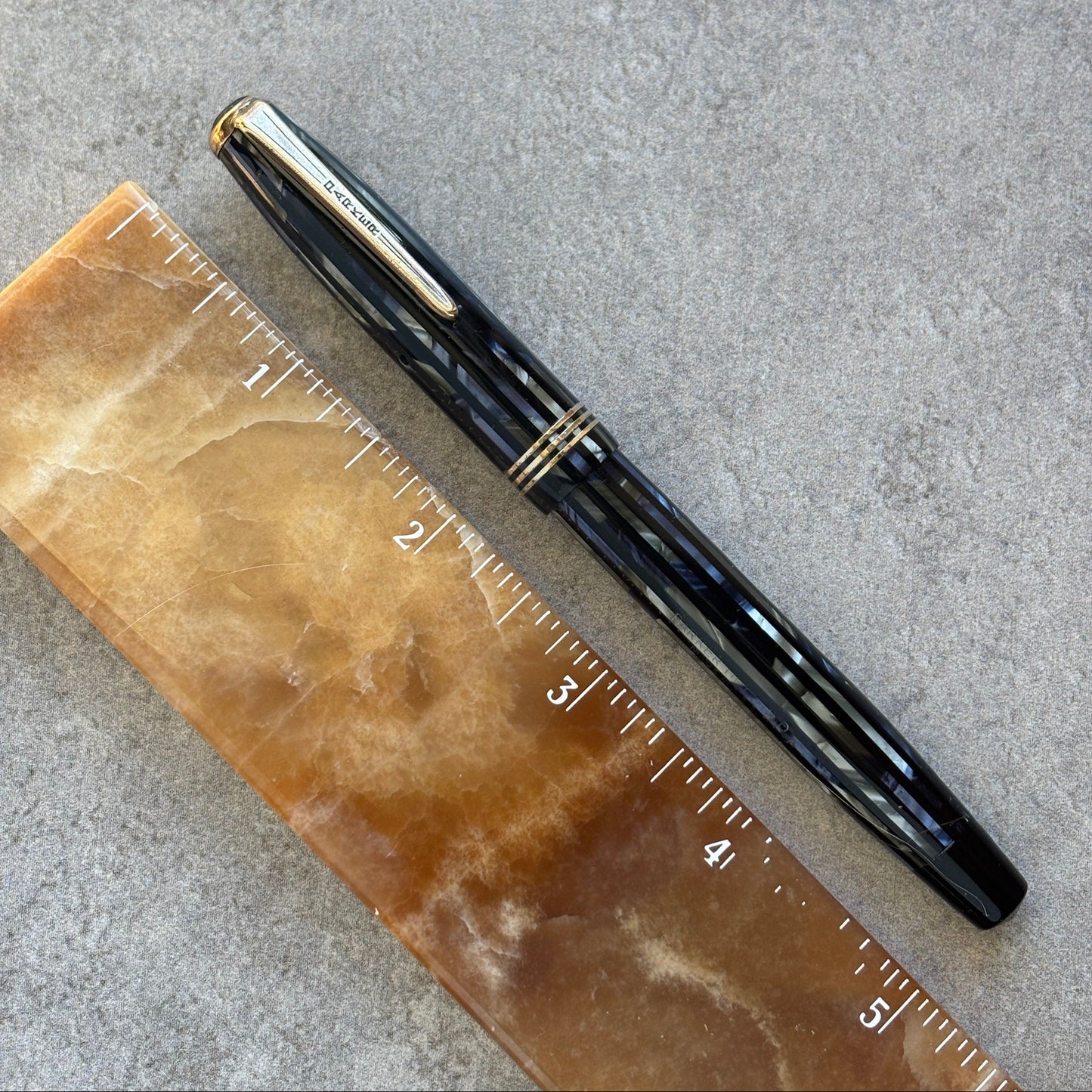 Blue pen on a brown ruler against a gray background