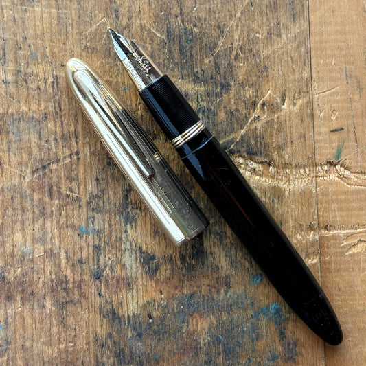 Sheaffer Triumph Crest Deluxe 1500 Fountain PenName/Type: Sheaffer Triumph Crest Deluxe Manufacture Year: 1940s Length: 5 1/4 Filling System: Vac-fil; restored with new sac Color/Pattern: Black barrel with gold-filled cap Nib Type/Condition and remarks: L