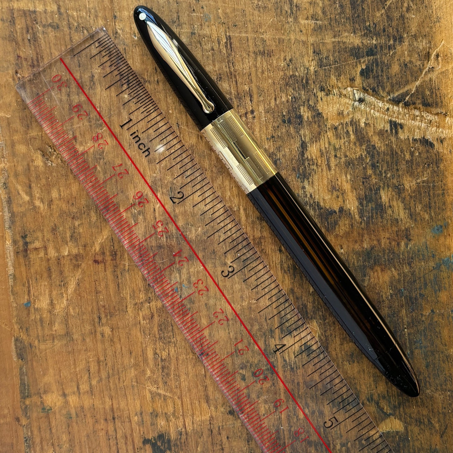 Sheaffer Triumph Vacuum-fil, Black, Extra-wide cap Band, Fine Two-tone NibLength: 5 1/8 Filling System: Vacuum-Fil; restored with new seals Color/Pattern: Black with gold-filled trim Nib Type/Condition and remarks: Fine two-tone 14K gold trim, smooth wet
