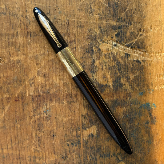 Sheaffer Triumph Vacuum-fil, Black, Extra-wide cap Band, Fine Two-tone NibLength: 5 1/8 Filling System: Vacuum-Fil; restored with new seals Color/Pattern: Black with gold-filled trim Nib Type/Condition and remarks: Fine two-tone 14K gold trim, smooth wet
