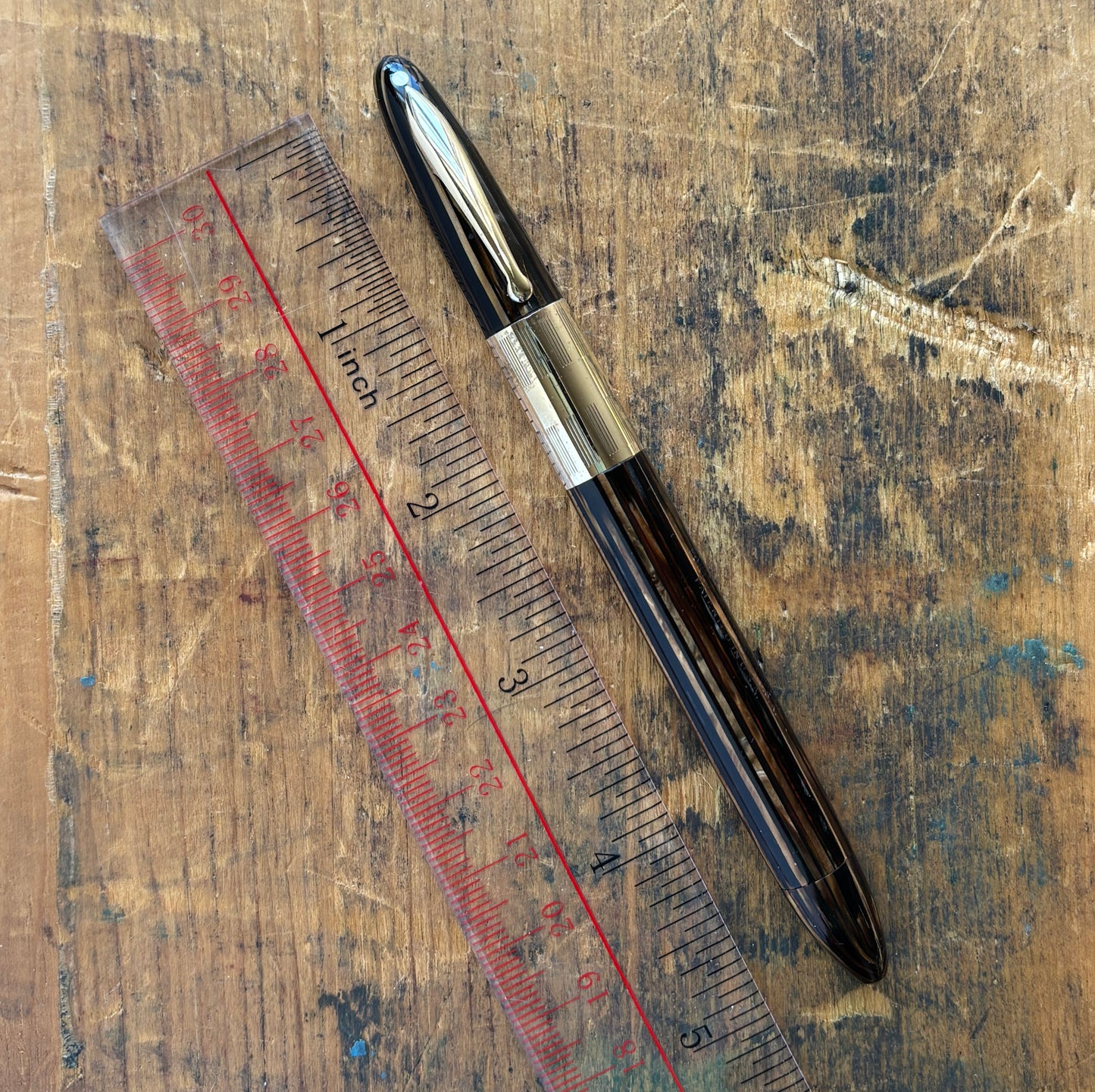Sheaffer Triumph Vacuum-fil, Golden Brown, Extra-wide cap Band, Fine Two-tone NibLength: 5 1/8 Filling System: Vacuum-Fil; restored with new seals Color/Pattern: Golden Brown with gold-filled trim Nib Type/Condition and remarks: Fine two-tone 14K gold tri