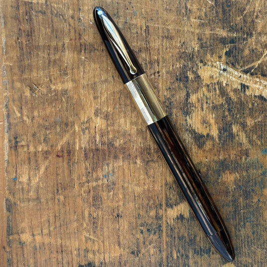 Sheaffer Triumph Vacuum-fil, Golden Brown, Extra-wide cap Band, Fine Two-tone NibLength: 5 1/8 Filling System: Vacuum-Fil; restored with new seals Color/Pattern: Golden Brown with gold-filled trim Nib Type/Condition and remarks: Fine two-tone 14K gold tri