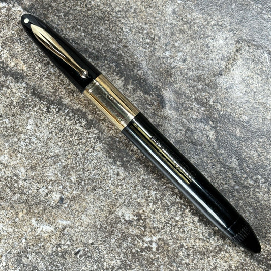 1940s Sheaffer Triumph Vacuum-fil, Extra-wide solid gold cap band, Black. Fine Two-tone Nib Length: 5 1/8 Filling System: Vacuum-Fill; restored with new seals Color/Pattern: Black with solid 14K gold trim Nib Type/Condition and remarks: Fine two-tone 14K