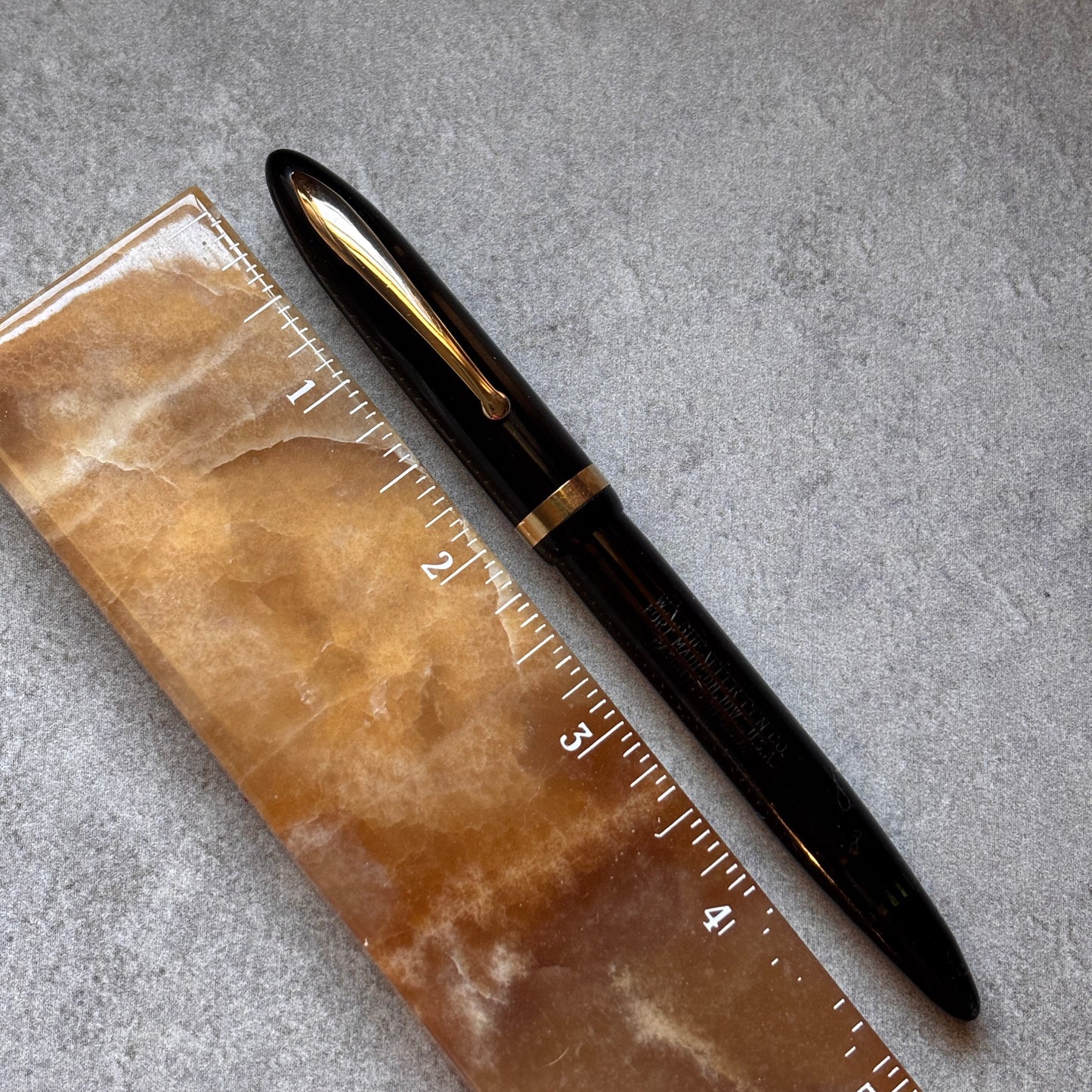 Black pen on a brown marble surface with a ruler