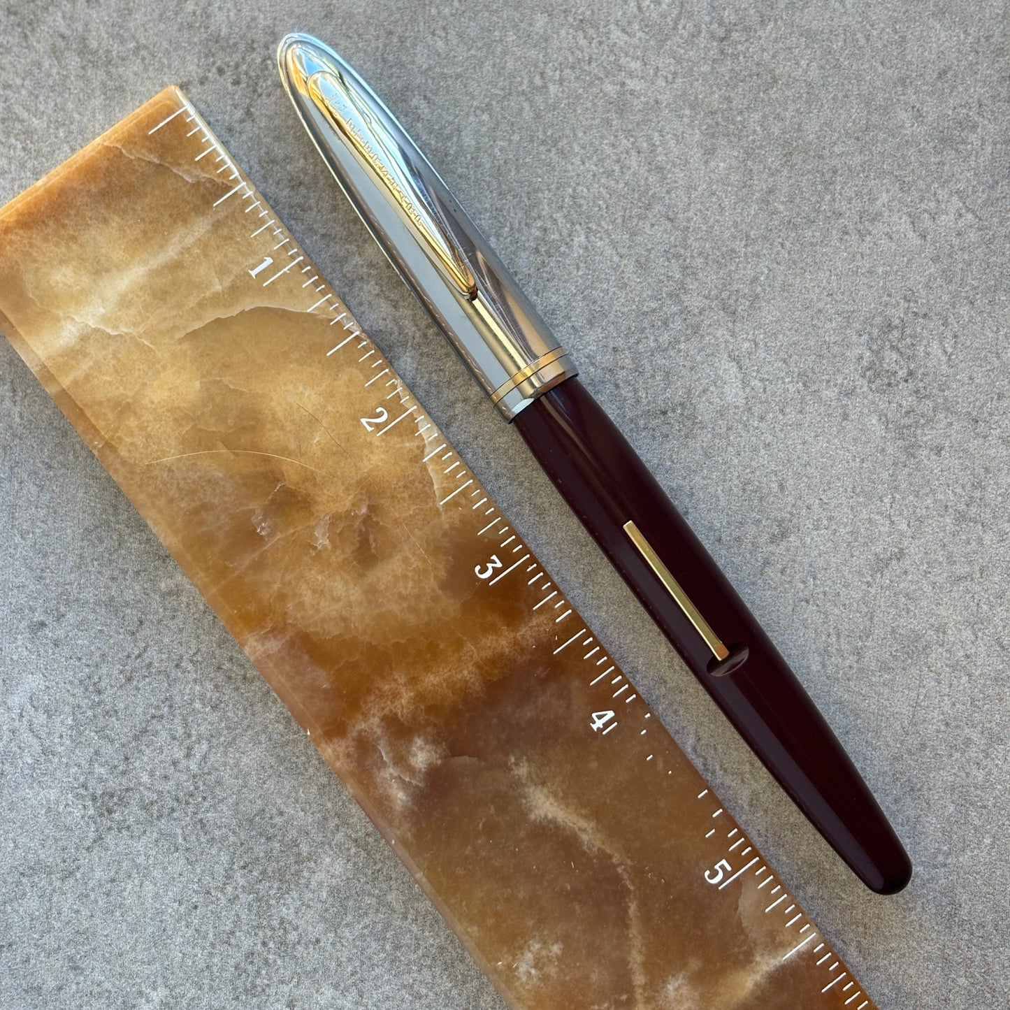 Fountain pen next to a ruler on a textured surface