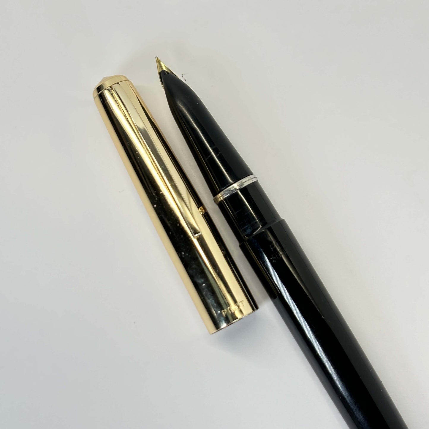 Pilot, Super 100, Flip Filler, Black with Gold Plated Cap Name/Type: Pilot Super 100 Manufacture Year: Early 1960s Length: 5 1/8 Filling System: Flip filler; restored with new sac Color/Pattern: Black with gold plated cap Nib Type/Condition and remarks: E