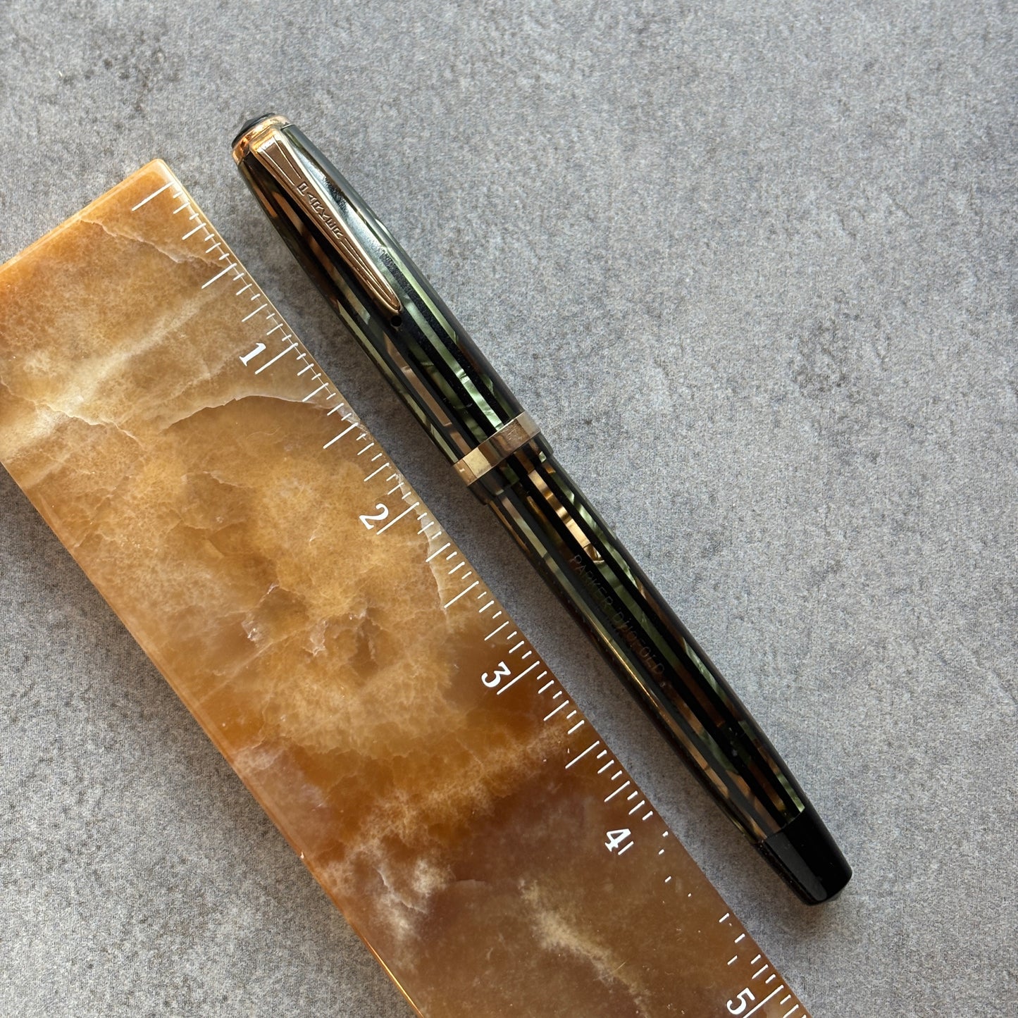 Fountain pen next to a ruler on a textured surface