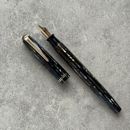 Black and blue fountain pen with gold accents on a gray concrete surface