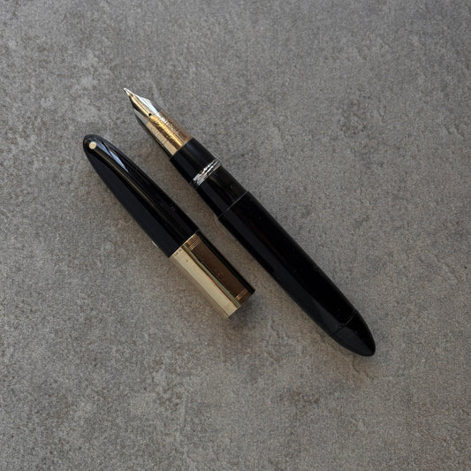 Black and gold fountain pen on a gray textured surface