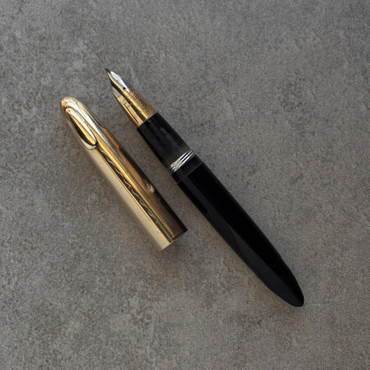 Gold and black fountain pen on a gray surface