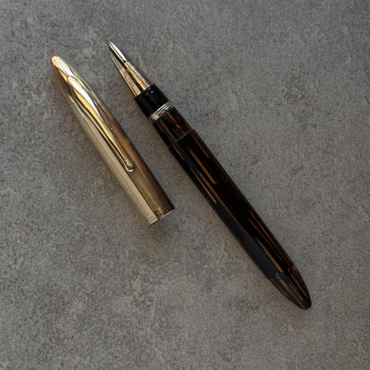 Fountain pen with gold cap and black body on a gray surface