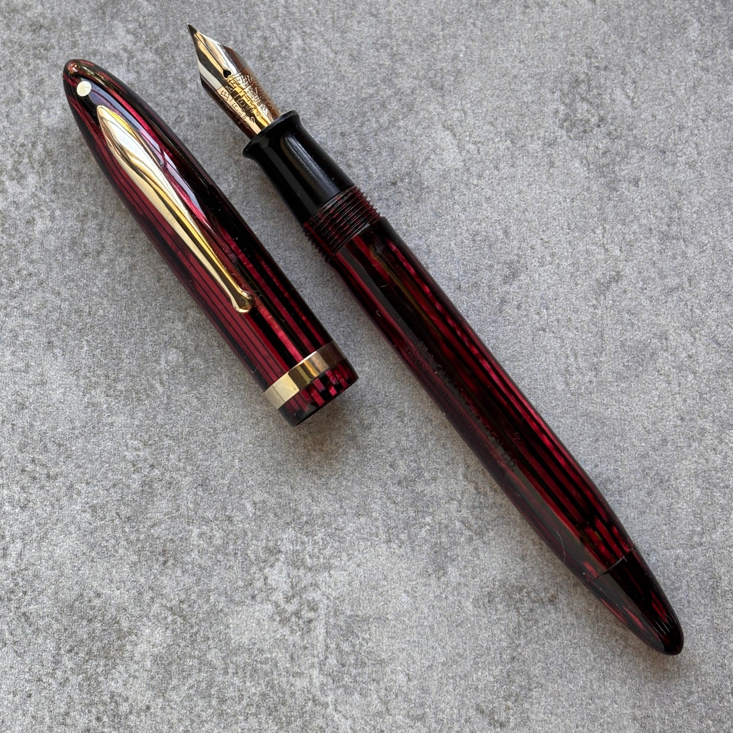 Red and gold fountain pen on a gray surface
