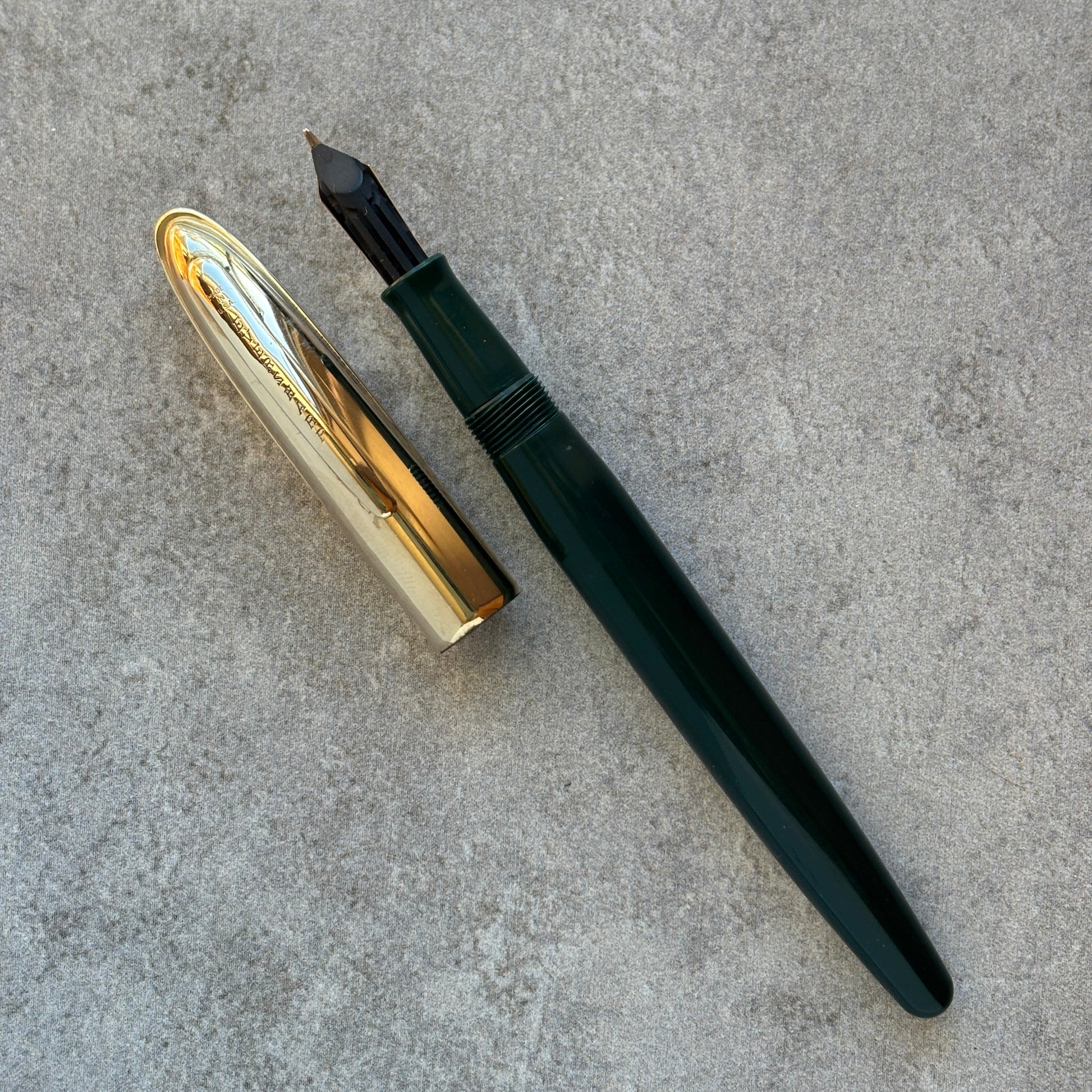 Fountain pen with gold cap and black body on a gray surface