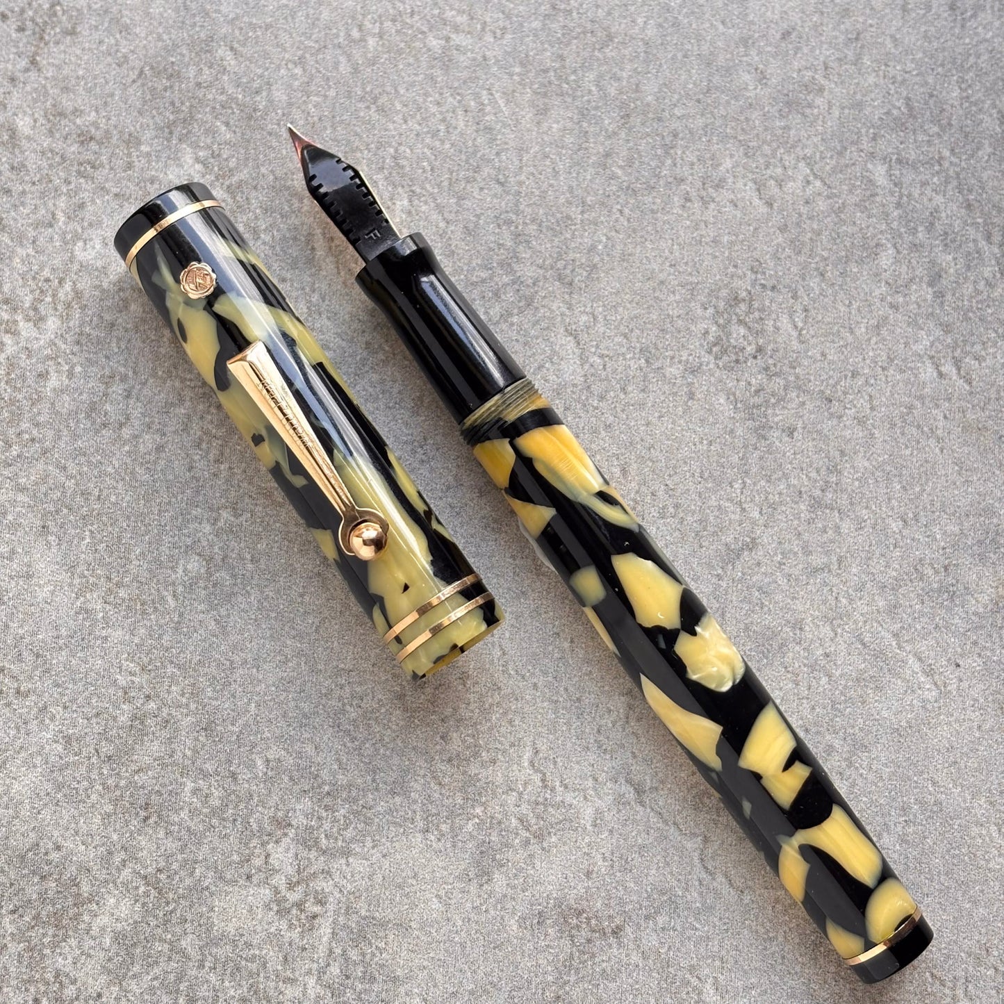 Fountain pen with black and yellow marbled design on a gray surface