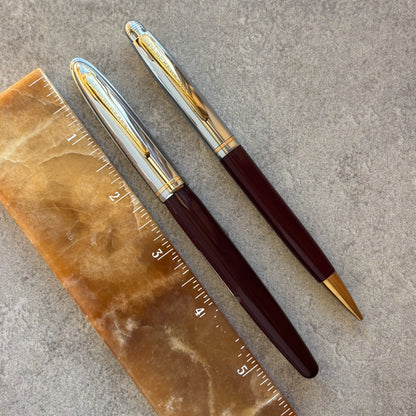 Two pens with gold accents on a stone surface next to a ruler.