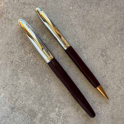 Two pens with gold and silver accents on a textured surface