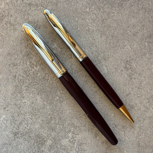 Two pens with gold and silver accents on a textured surface