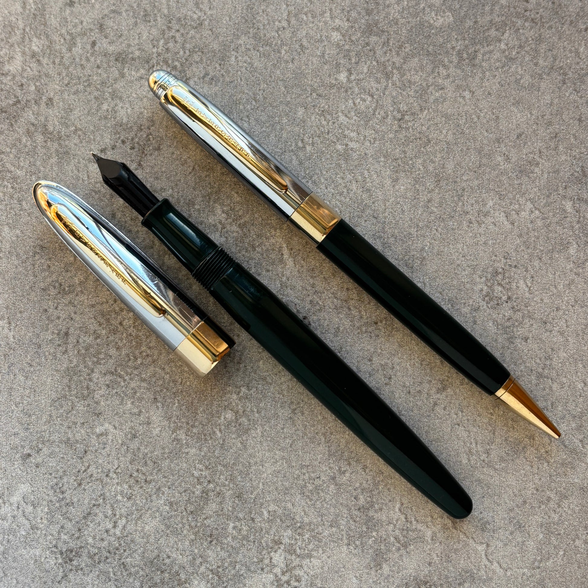 Two fountain pens,  on a textured surface.