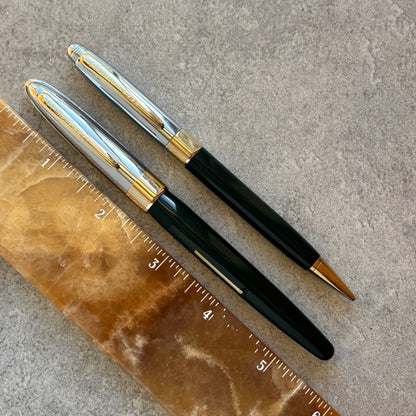 Two pens with gold accents on a textured surface next to a ruler.