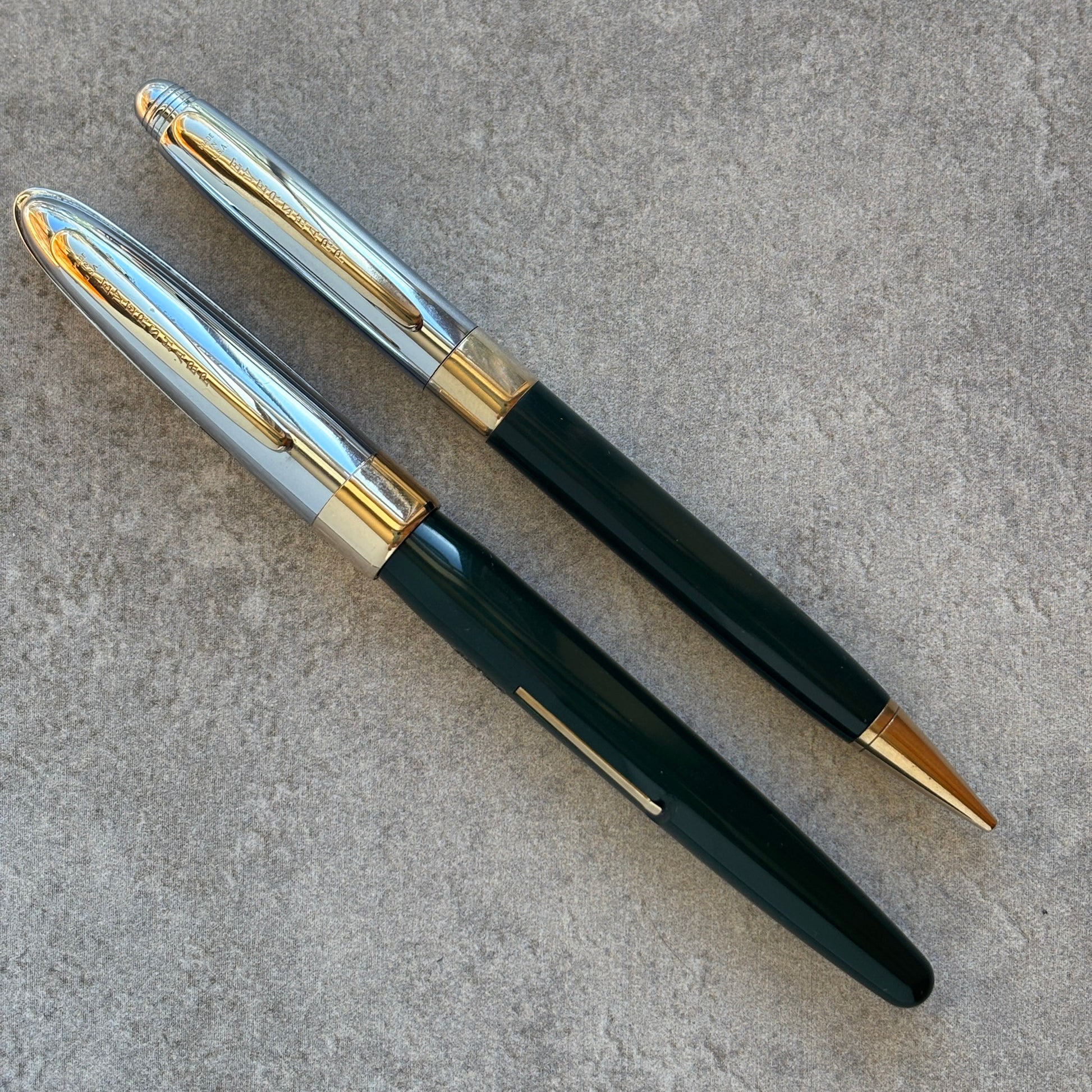 Pen with dark green body, gold accents, and silver clip on a gray surface