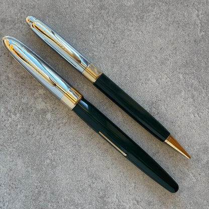 Pen with dark green body, gold accents, and silver clip on a gray surface