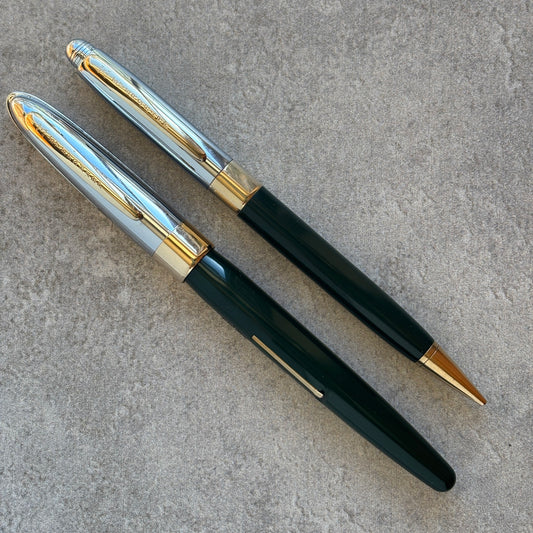 Pen with dark green body, gold accents, and silver clip on a gray surface