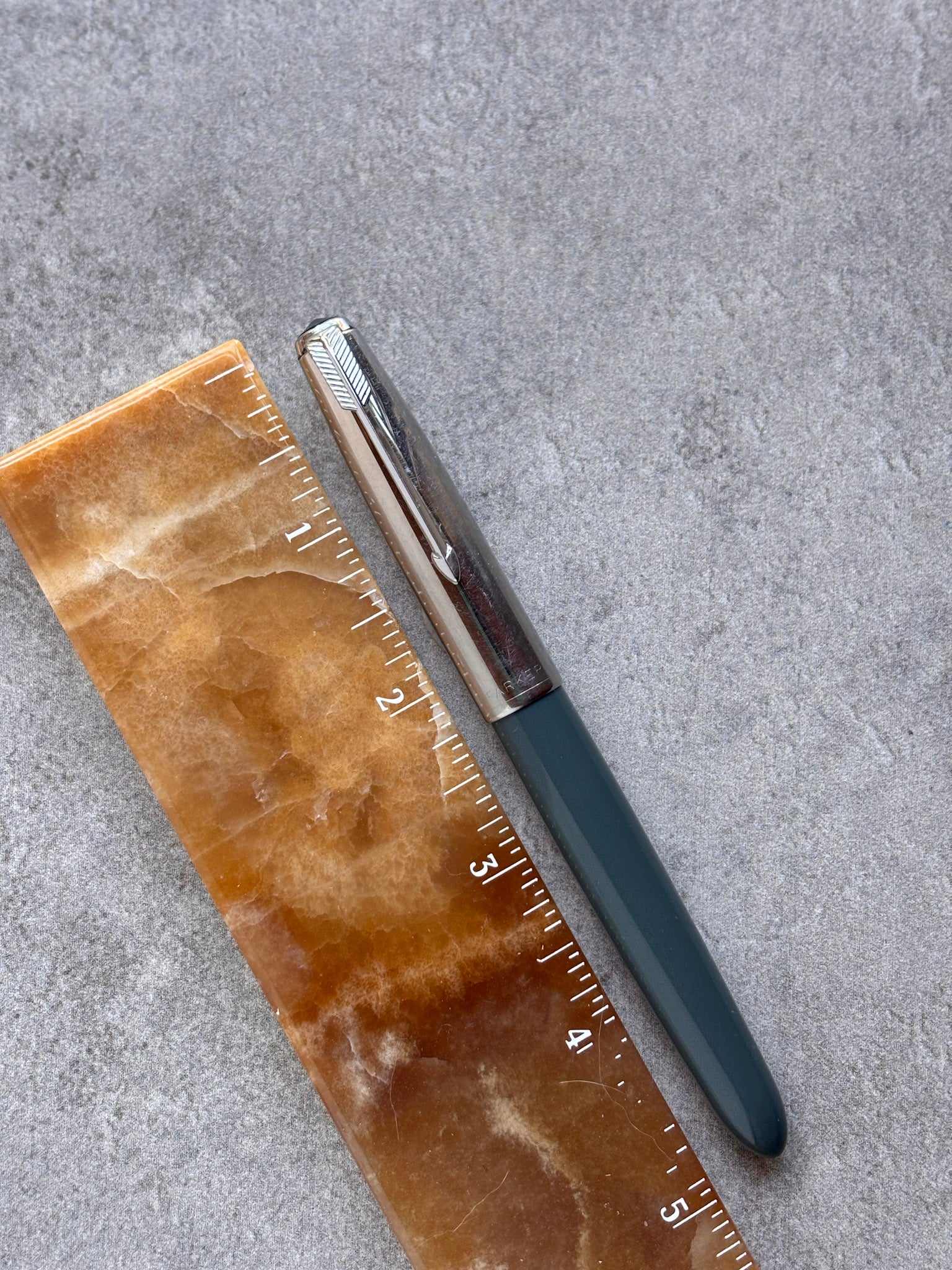 Pen and ruler on a textured gray surface