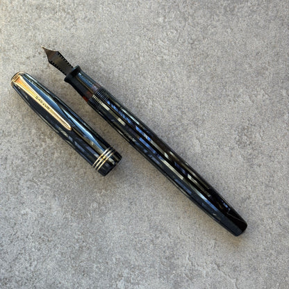 Blue fountain pen and cap on a gray concrete surface