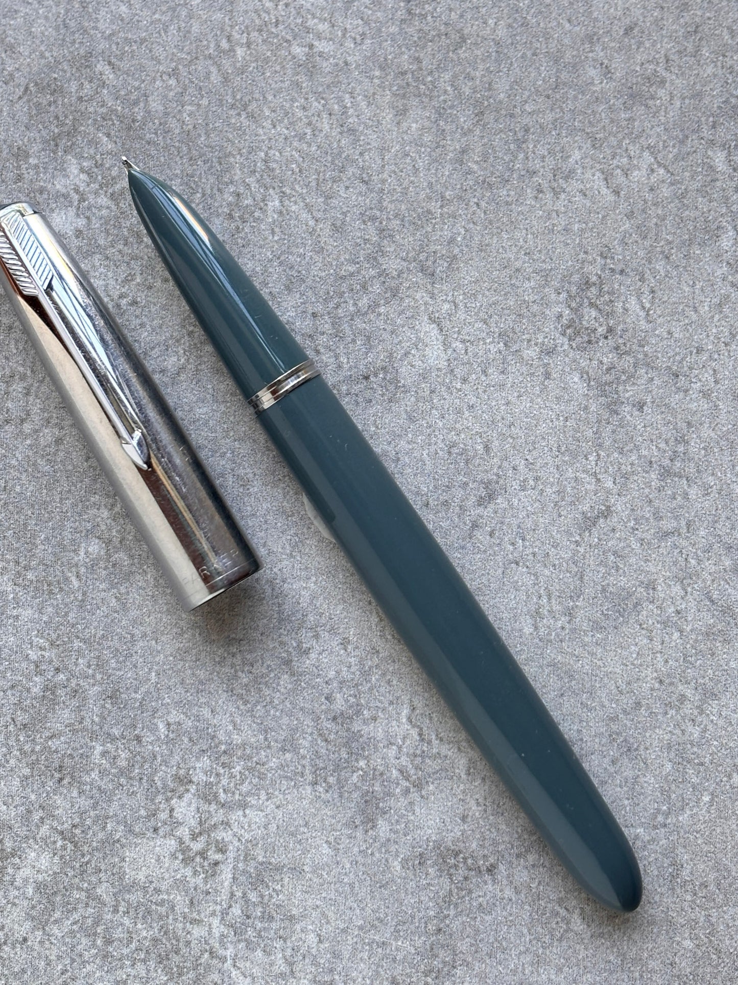 Fountain pen and cap on a textured gray surface