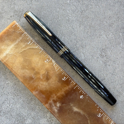 Blue pen on a brown ruler against a gray background
