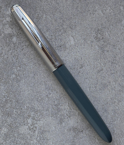 Pen with metallic clip and black body on a textured gray surface