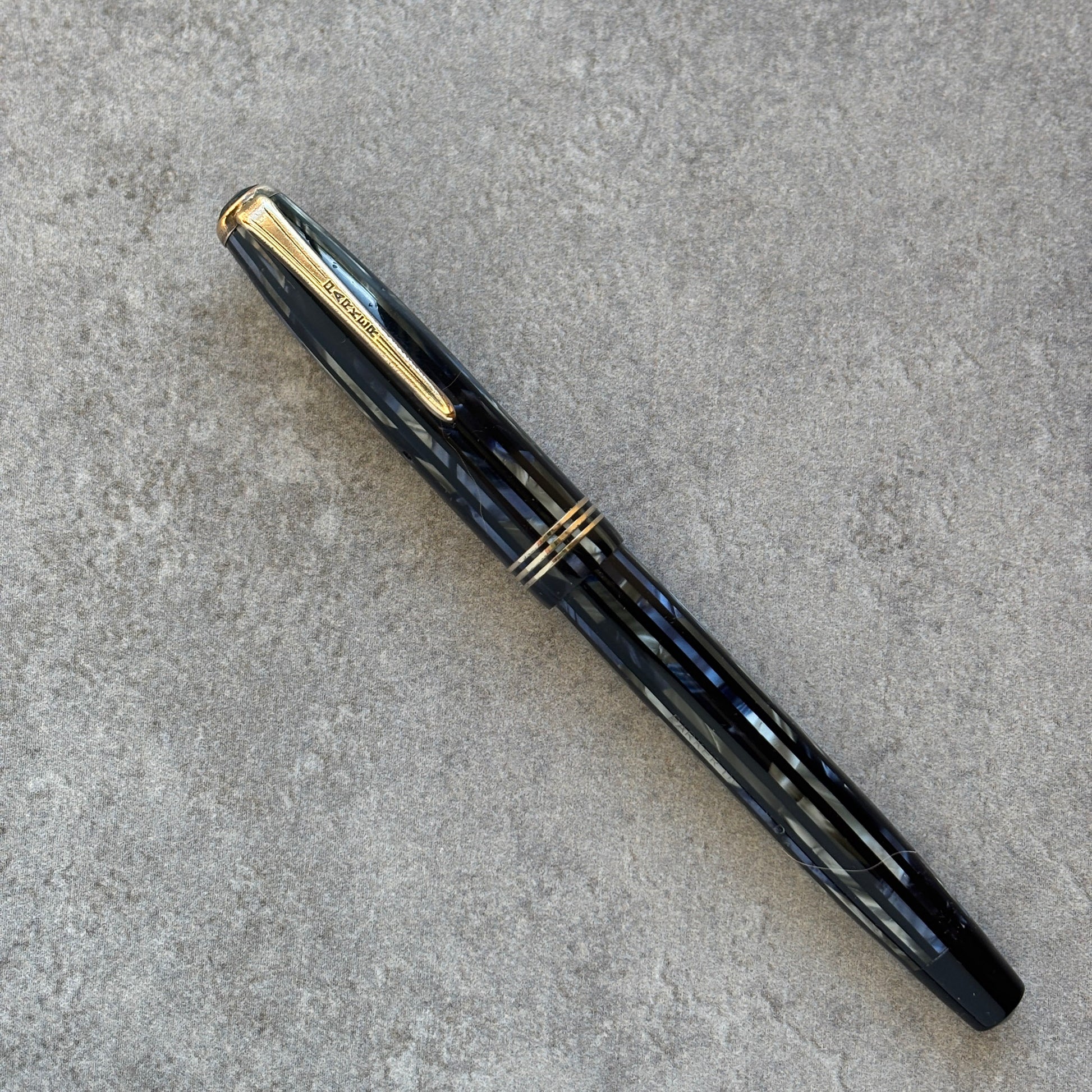 Blue fountain pen with gold accents on a gray concrete surface