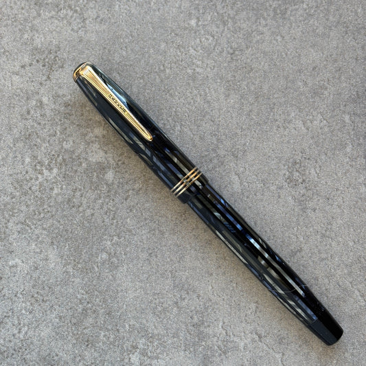 Blue fountain pen with gold accents on a gray concrete surface