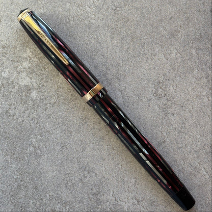 Black and red fountain pen with gold accents on a gray surface