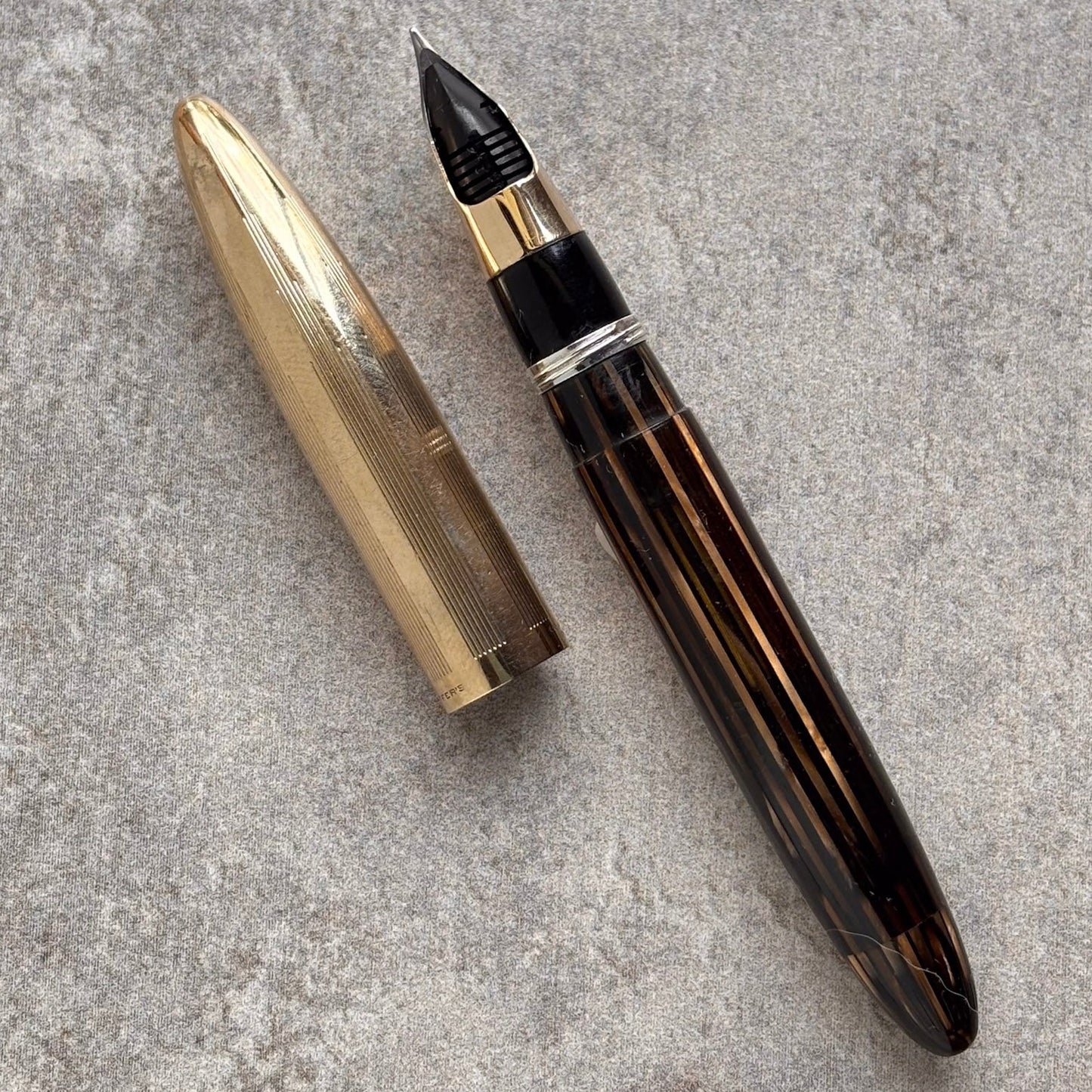 Fountain pen with gold cap on a gray textured surface