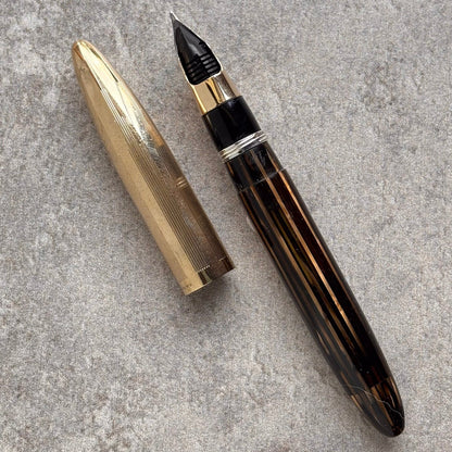 Fountain pen with gold cap on a gray textured surface