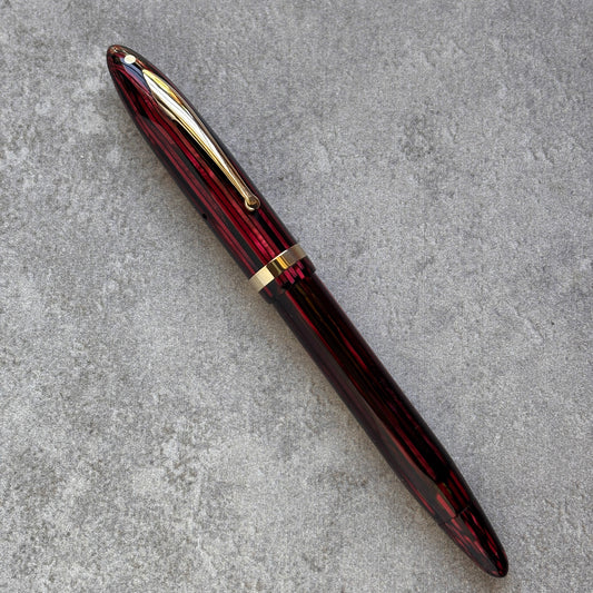 Red and gold pen on a gray concrete surface