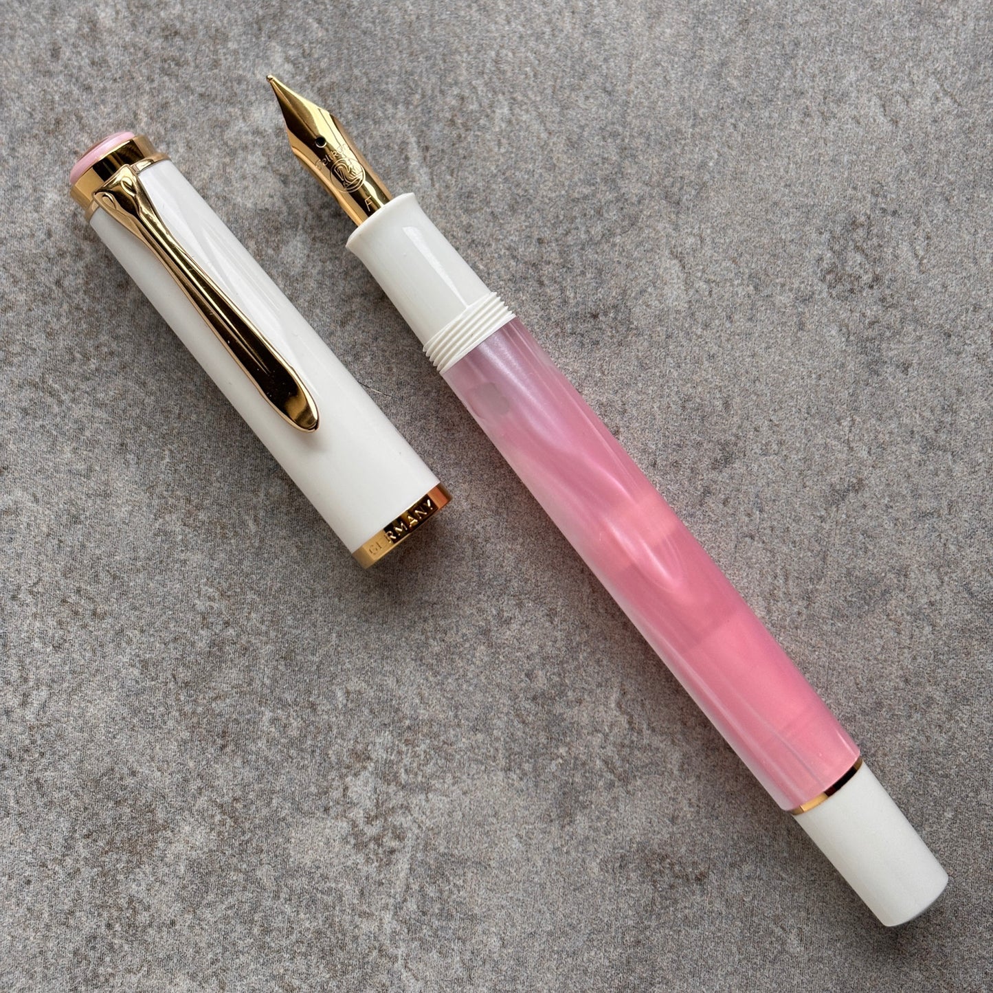 Fountain pen with white and pink design on a gray surface