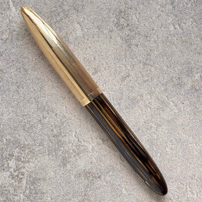 Pen with gold cap and black body on a gray concrete surface