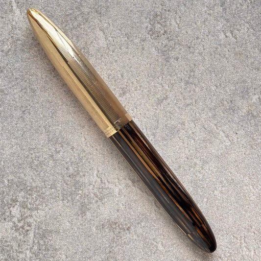 Pen with gold cap and black body on a gray concrete surface
