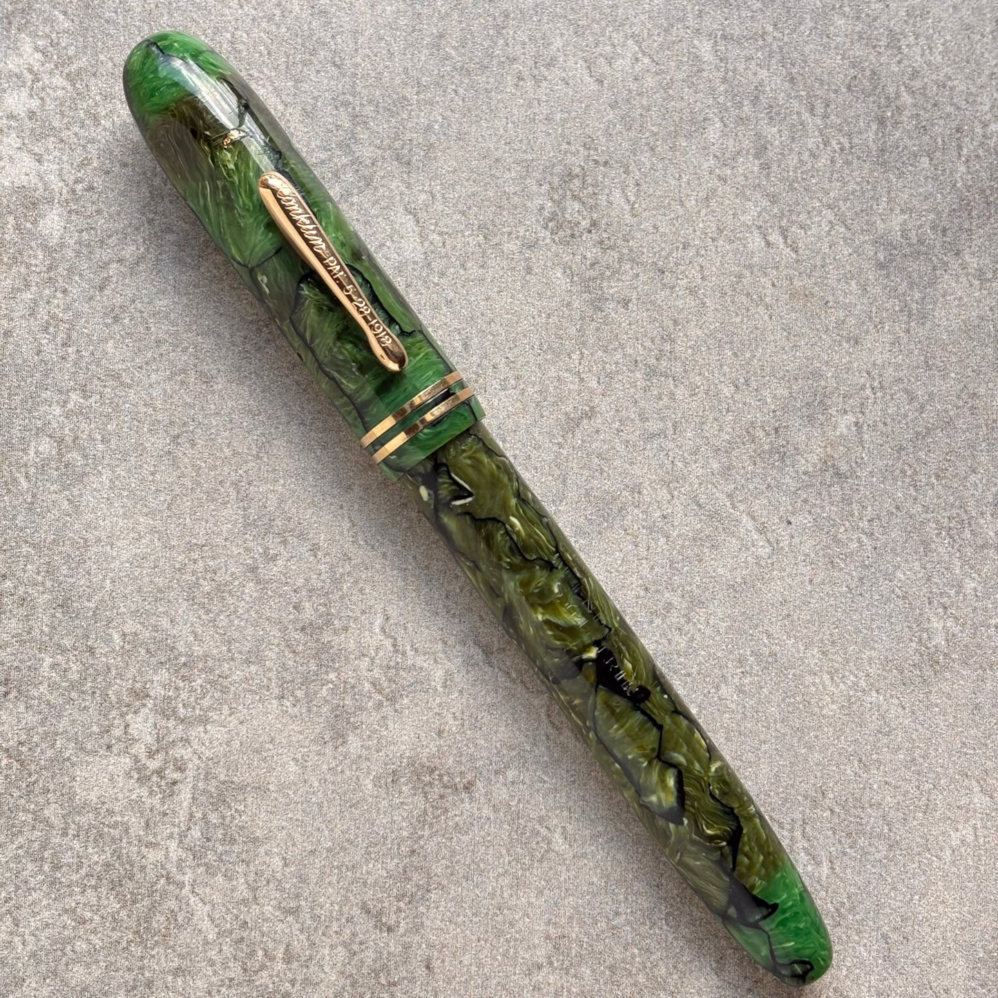 Green pen with gold accents on a gray surface
