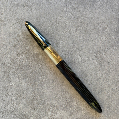 green and gold fountain pen on a gray concrete surface