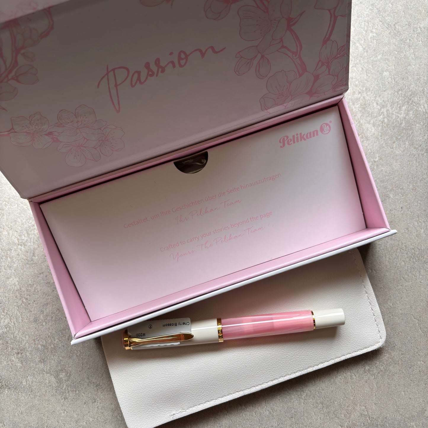 Pink and white Pelikan pen in an open box with 'Passion' text on a light gray background