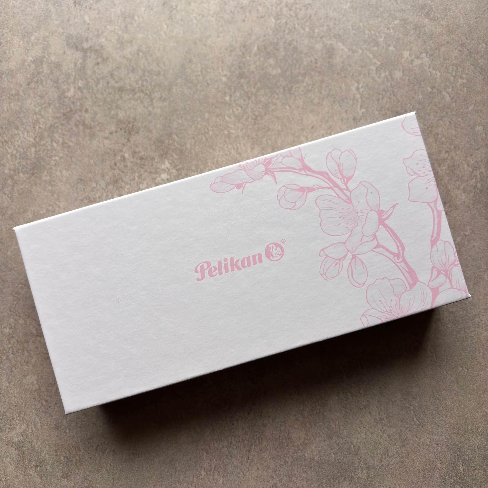White box with pink floral design and 'Pelikan' logo on a gray surface