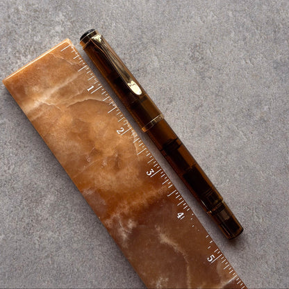 Marble-patterned ruler and brown pen on a gray surface