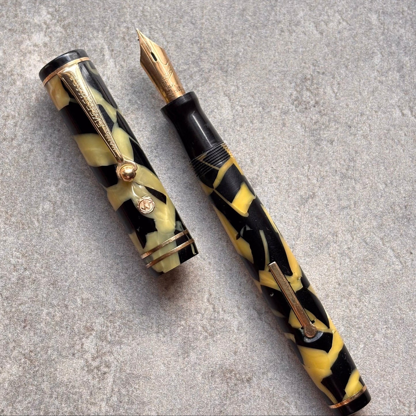 Fountain pen with black and yellow marbled design on a gray surface