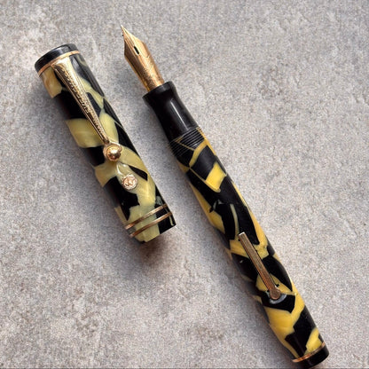 Fountain pen with black and yellow marbled design on a gray surface