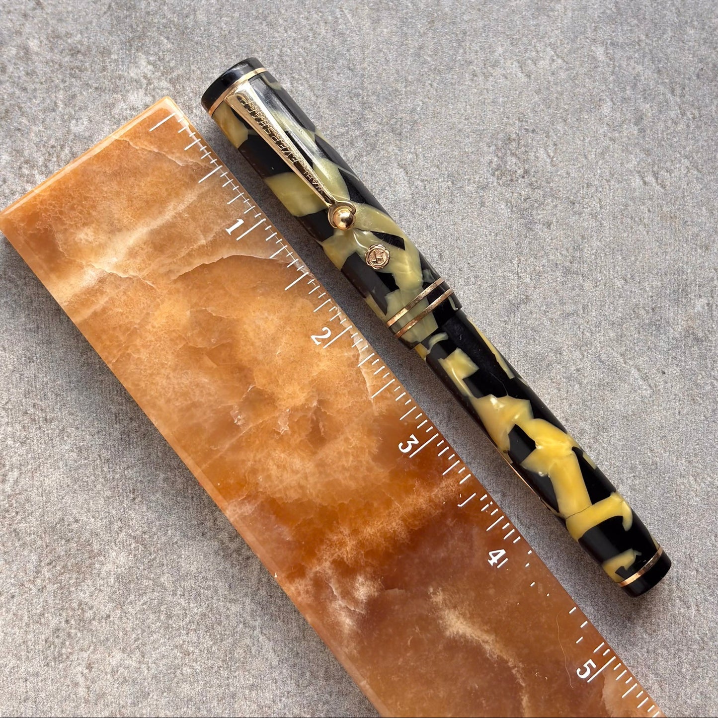 Pen with tortoiseshell pattern next to a ruler on a gray surface
